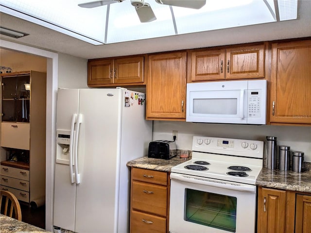 kitchen with ceiling fan, light stone counters, and white appliances