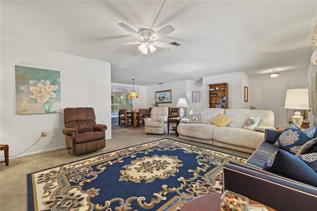 living room with ceiling fan, light colored carpet, and a textured ceiling