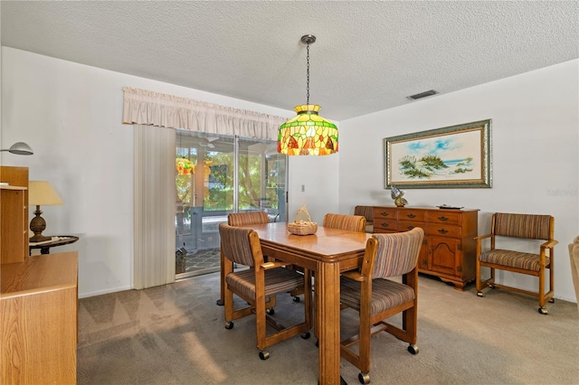 carpeted dining room featuring a textured ceiling