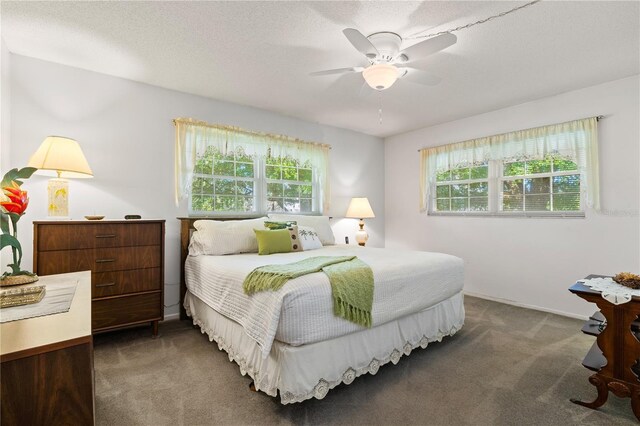 bedroom with a textured ceiling, ceiling fan, and dark colored carpet