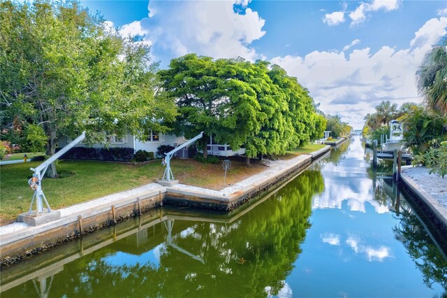 view of dock with a lawn and a water view