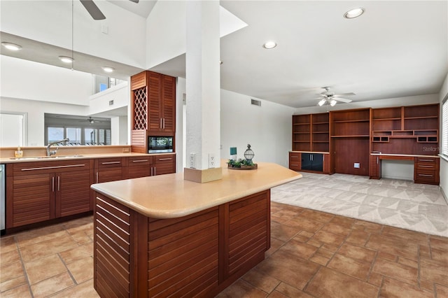 kitchen featuring ceiling fan, sink, pendant lighting, and a high ceiling