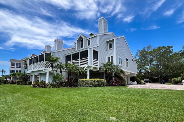 view of side of property featuring a sunroom, a garage, and a lawn