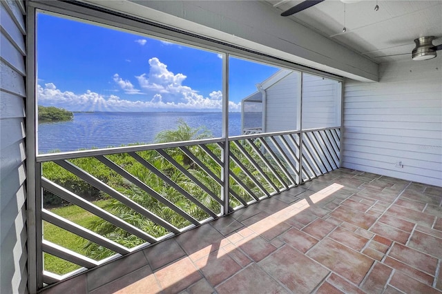 unfurnished sunroom featuring ceiling fan and a water view