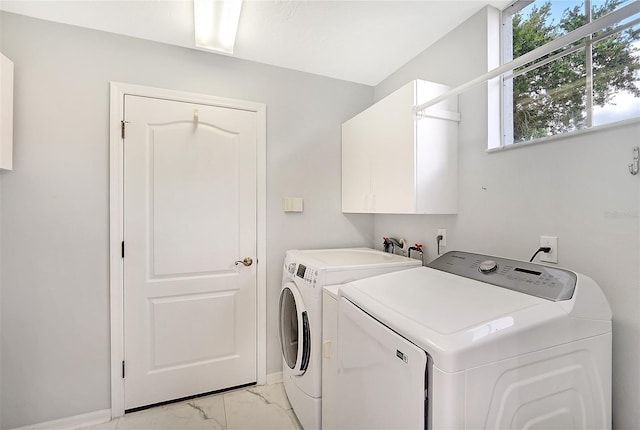 washroom featuring washing machine and dryer, cabinets, and light tile patterned floors