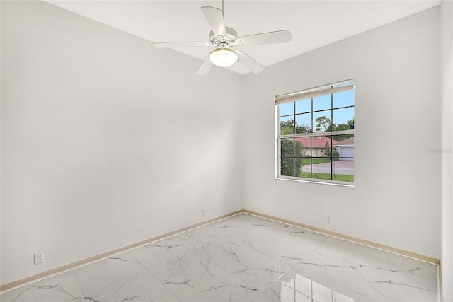 empty room featuring ceiling fan, marble finish floor, and baseboards