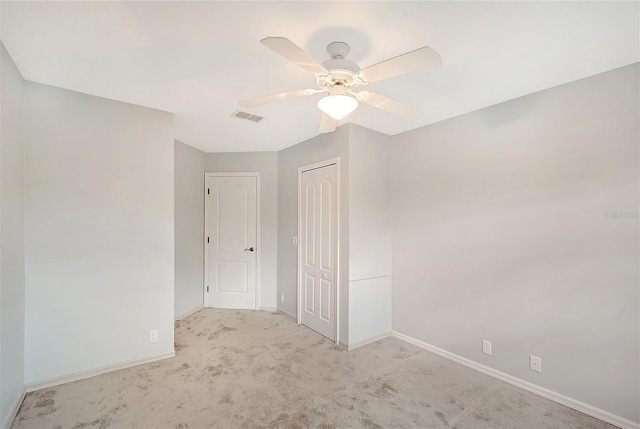 carpeted spare room featuring visible vents, ceiling fan, and baseboards