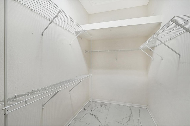 walk in closet featuring marble finish floor