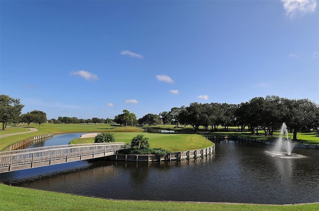 view of community with a water view, view of golf course, and a lawn