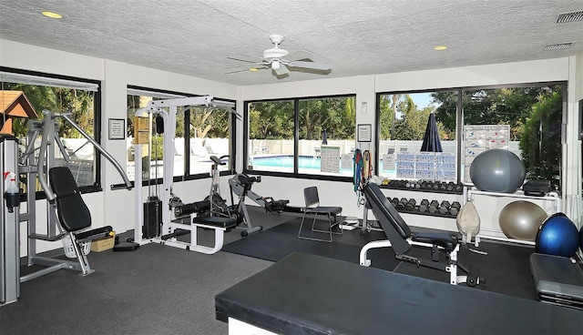 gym featuring ceiling fan and a textured ceiling