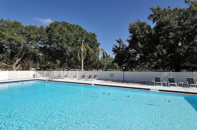 pool with a patio area and fence