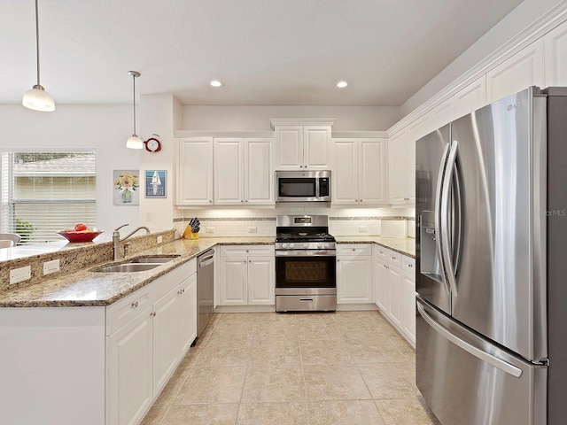 kitchen featuring stainless steel appliances, stone counters, sink, pendant lighting, and kitchen peninsula