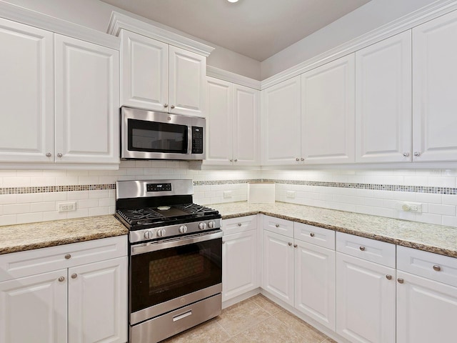 kitchen featuring tasteful backsplash, white cabinetry, appliances with stainless steel finishes, and light tile patterned floors