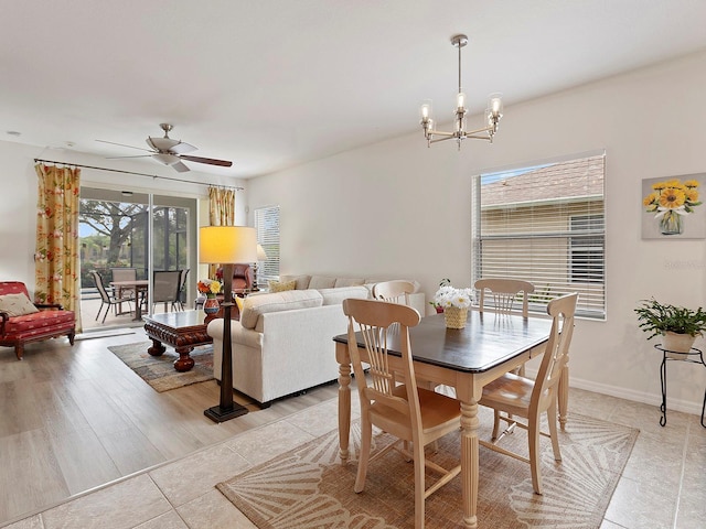 dining space with ceiling fan with notable chandelier and light hardwood / wood-style flooring