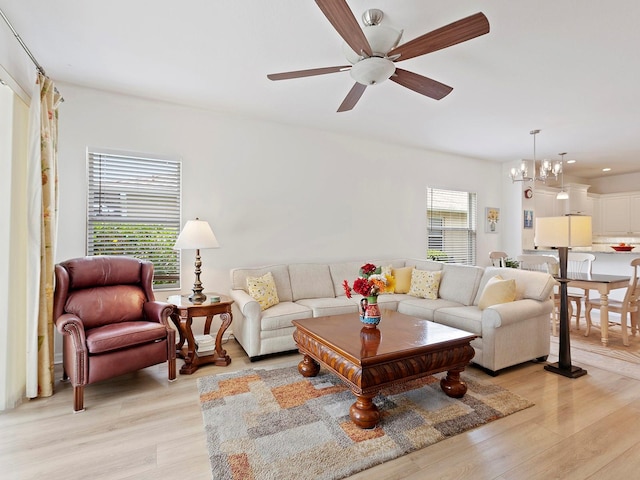 living room featuring a wealth of natural light, light hardwood / wood-style flooring, and ceiling fan with notable chandelier