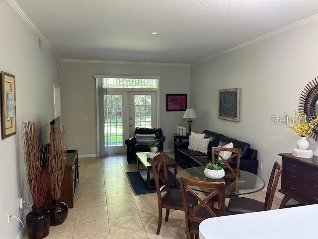 tiled dining area featuring ornamental molding and french doors