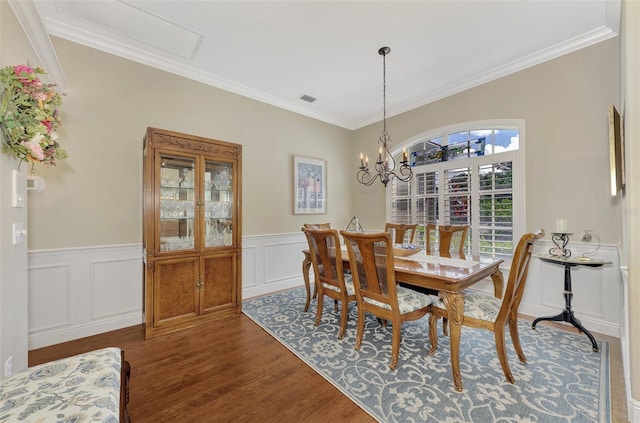 dining area with hardwood / wood-style flooring, an inviting chandelier, and ornamental molding