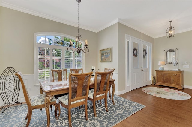 dining area with a notable chandelier, ornamental molding, and dark hardwood / wood-style floors