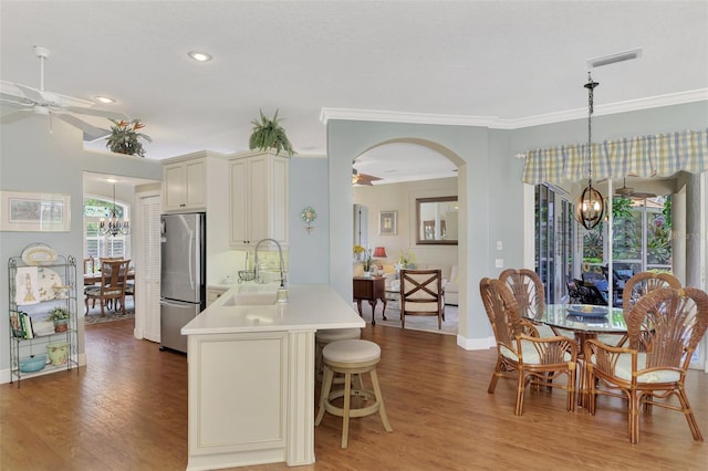 kitchen with ceiling fan with notable chandelier, kitchen peninsula, stainless steel fridge, and hardwood / wood-style floors