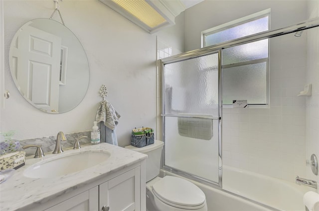 full bathroom with combined bath / shower with glass door, toilet, and vanity