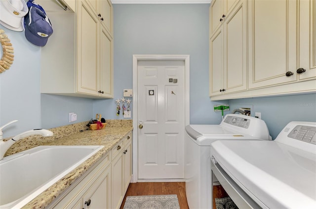 clothes washing area featuring sink, light hardwood / wood-style floors, cabinets, and washing machine and clothes dryer