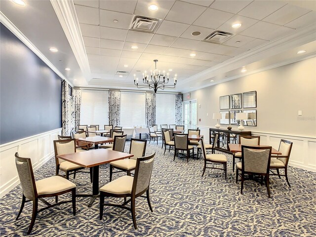 dining area featuring a raised ceiling, crown molding, a notable chandelier, and carpet flooring