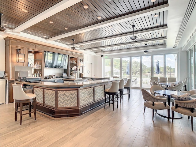 kitchen with light wood-type flooring, a breakfast bar area, and beam ceiling