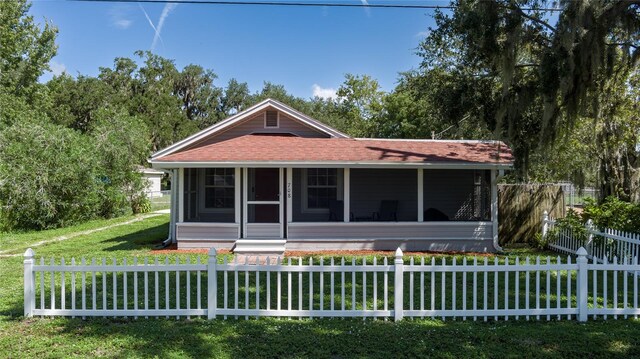 view of front of home with a sunroom and a front lawn