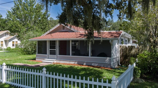 view of front of house with a front yard and a sunroom