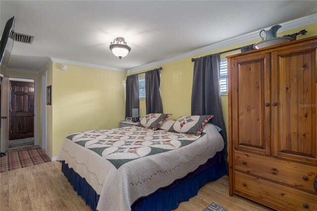 bedroom featuring crown molding, multiple windows, and light hardwood / wood-style flooring