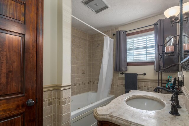 bathroom with vanity, tile walls, a textured ceiling, and shower / bath combo with shower curtain