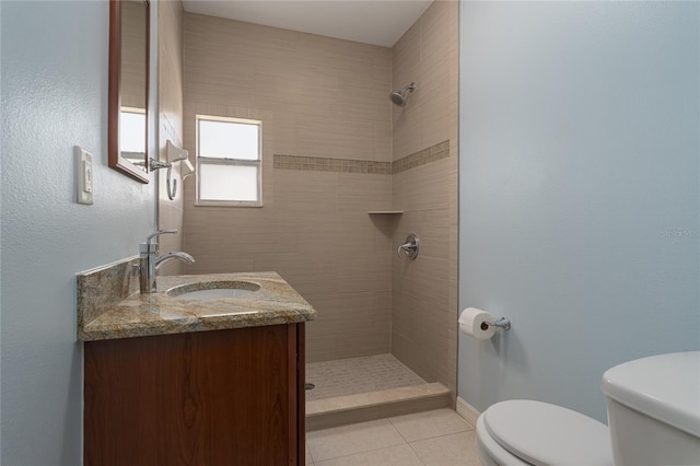 bathroom featuring vanity, toilet, tiled shower, and tile patterned floors