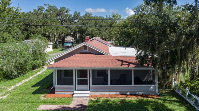 back of house featuring a lawn and a sunroom