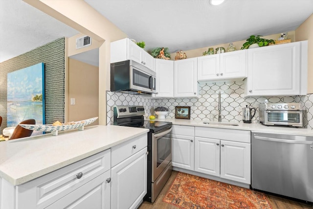 kitchen featuring backsplash, sink, stainless steel appliances, and light hardwood / wood-style flooring