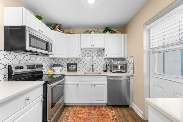 kitchen featuring backsplash, stainless steel appliances, sink, white cabinets, and hardwood / wood-style flooring