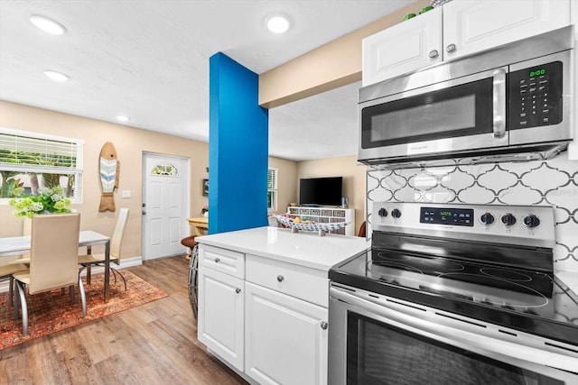 kitchen featuring white cabinetry, backsplash, appliances with stainless steel finishes, and light hardwood / wood-style floors