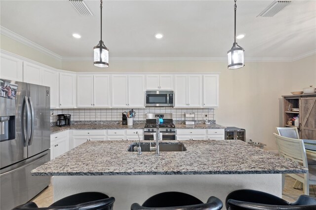 kitchen with stainless steel appliances, decorative backsplash, white cabinetry, and hanging light fixtures