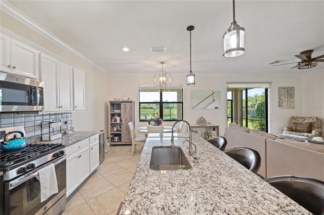 kitchen with stainless steel appliances, decorative backsplash, white cabinetry, sink, and light tile patterned floors