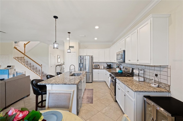 kitchen with tasteful backsplash, an island with sink, light stone counters, sink, and stainless steel appliances