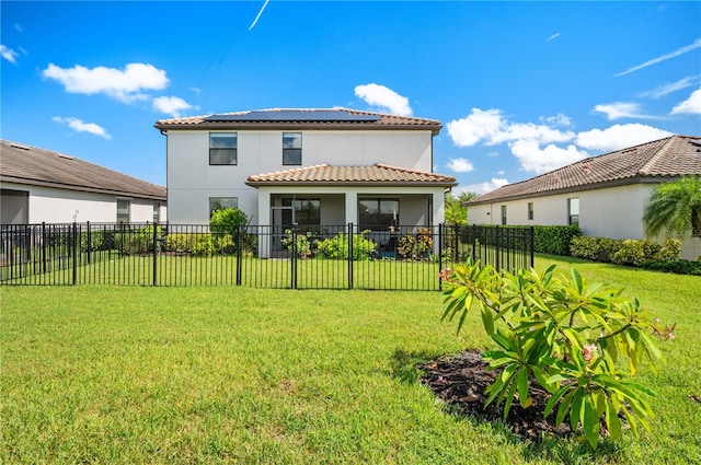 back of property with a lawn and solar panels