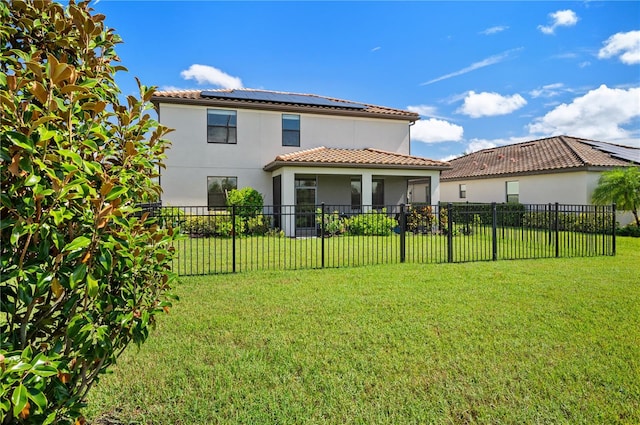 rear view of house with solar panels and a yard