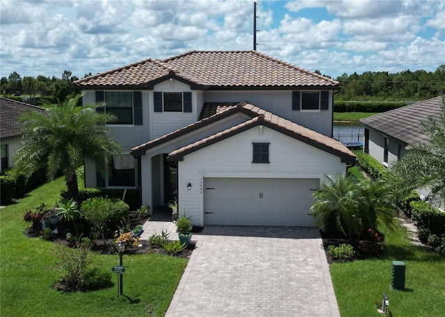 mediterranean / spanish home with decorative driveway, a front yard, and a tile roof