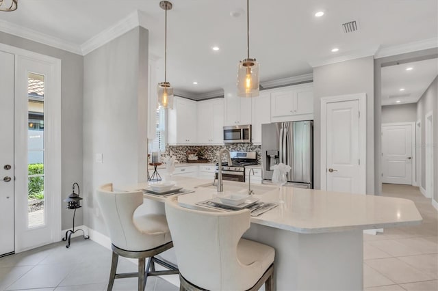 kitchen featuring a kitchen breakfast bar, appliances with stainless steel finishes, pendant lighting, decorative backsplash, and white cabinets