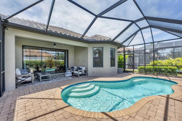 view of pool with ceiling fan, a patio, glass enclosure, and outdoor lounge area