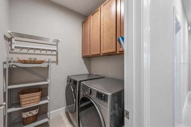 clothes washing area featuring washer and dryer, cabinets, and light tile patterned floors