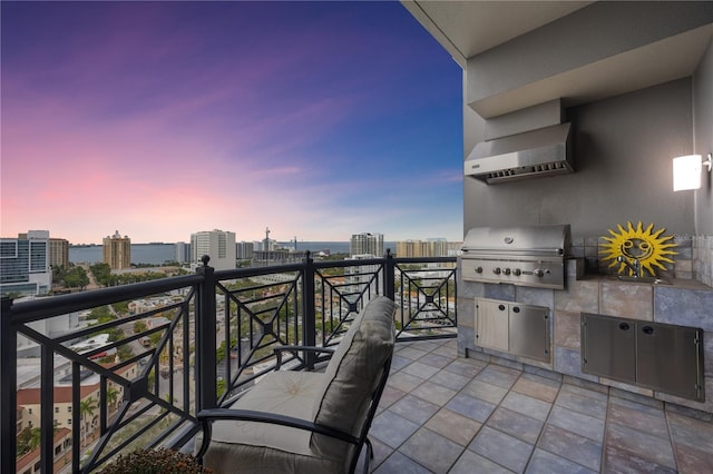 patio terrace at dusk featuring a balcony, a view of city, and grilling area