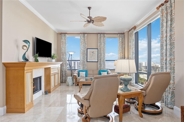 living room featuring ornamental molding, a wealth of natural light, a glass covered fireplace, and ceiling fan