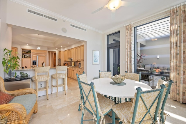 tiled dining area featuring ceiling fan, a raised ceiling, and crown molding