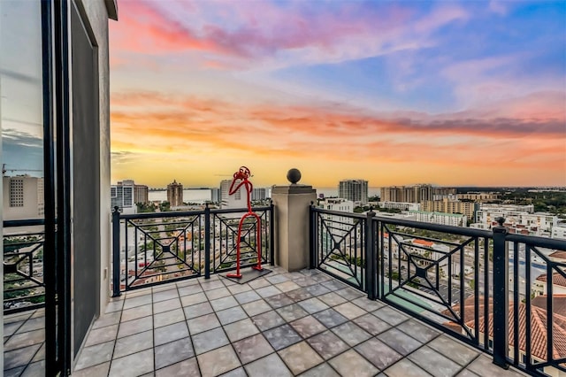 balcony at dusk featuring a view of city