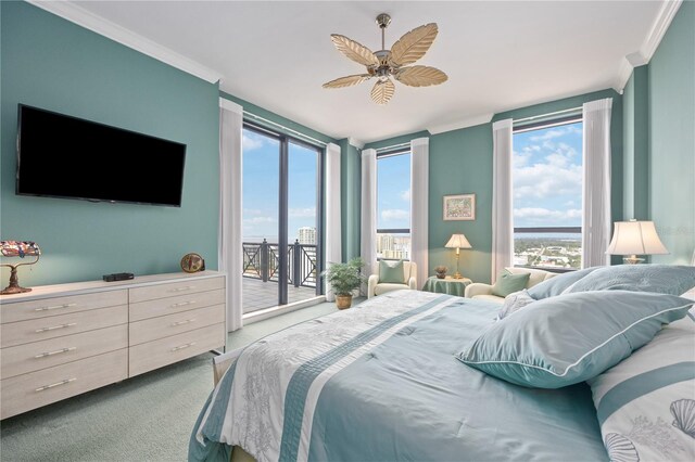 carpeted bedroom featuring ceiling fan, expansive windows, crown molding, and access to exterior